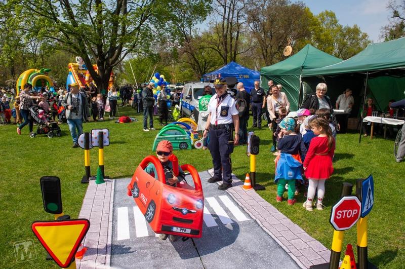 Dzieci bawiące się na makiecie miasteczka ruchu drogowego pod opieką strażnika Straży Miejskiej